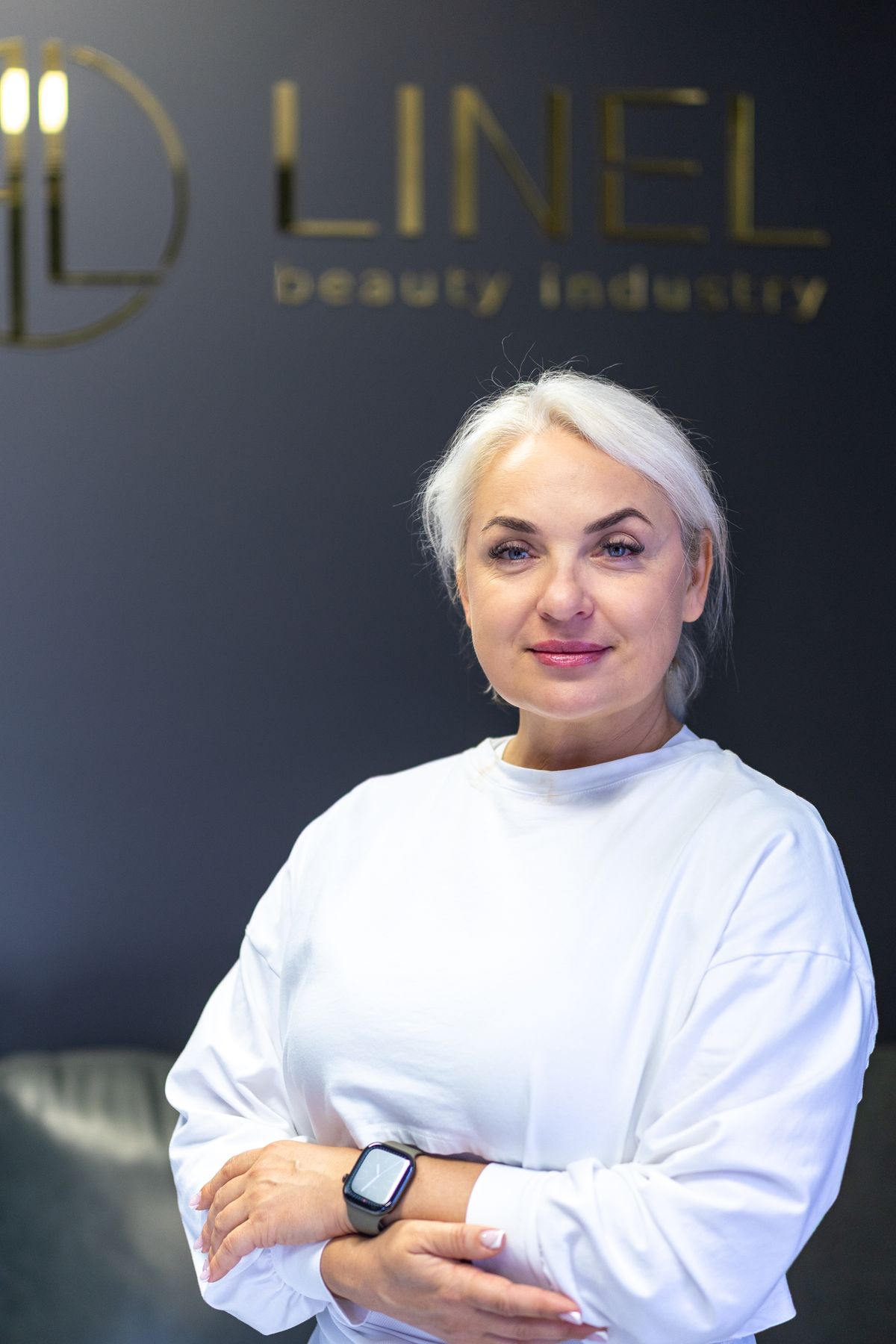 Olena Burykina, arms crossed, in front of the LINEL sign